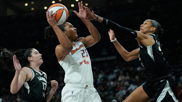 Phoenix Mercury forward Alyssa Thomas (25) shoots over Las Vegas Aces center Megan Gustafson, left, and center A'ja Wilson, right, during the first half in Game 1 of a WNBA basketball final playoff series Friday, Oct. 3, 2025, in Las Vegas. (AP Photo/John Locher)