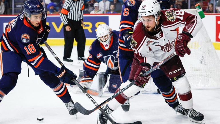 Peterborough Petes forward Connor Lockhart, right, chases the puck with Kamloops Blazers defenceman Harrison Brunicke, left, as goalie Dylan Ernst, centre, looks on during first period Memorial Cup hockey action in Kamloops, B.C., Thursday, June 1, 2023.THE CANADIAN PRESS/Jeff McIntosh