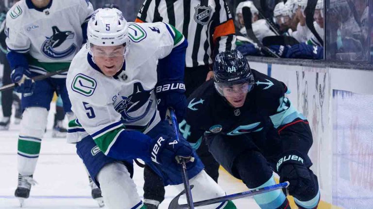 Vancouver Canucks defenseman Tom Willander (5) and Seattle Kraken forward Jake O'Brien, right, vie for the puck during the first period of a preseason NHL hockey game Sunday, Sept. 21, 2025, in Seattle. (John Froschauer/AP)