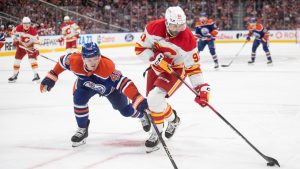 Calgary Flames' Nazem Kadri (91) and Edmonton Oilers' Ty Emberson (49) battle for the puck during third period NHL action, in Edmonton on Wednesday, October 8, 2025. (Jason Franson/CP)