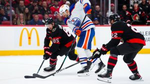 Edmonton Oilers' Evan Bouchard moves the puck between Ottawa Senators' Jake Sanderson (85) and Michael Amadio (22) during first period NHL action in Ottawa on Tuesday, Oct. 21, 2025. (Sean Kilpatrick/CP)
