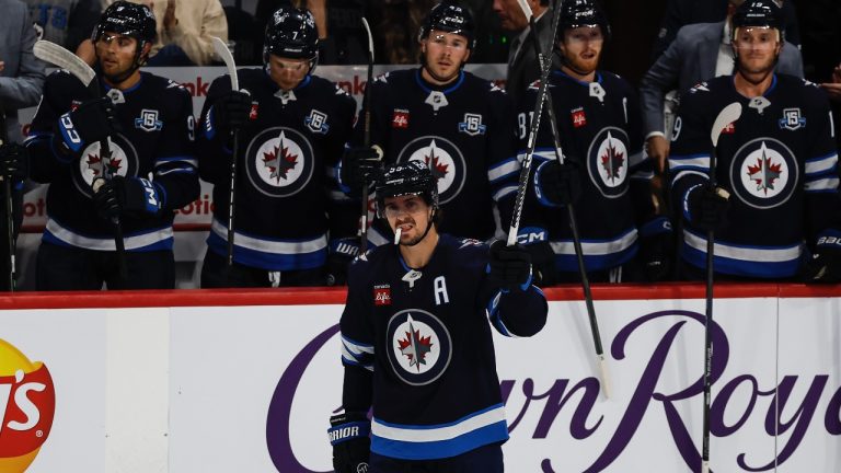 Winnipeg Jets' Mark Scheifele raises his stick to the crowd as he is announced as franchise point leader during first period NHL action against the Nashville Predators in Winnipeg on Saturday, October 18, 2025. (THE CANADIAN PRESS/John Woods)