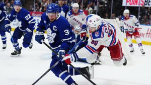 Toronto Maple Leafs' Auston Matthews (34) battles for the puck with New York Rangers' Will Cuylle (50) during first period NHL action in Toronto on Thursday, Oct. 16, 2025. (Nathan Denette/CP)