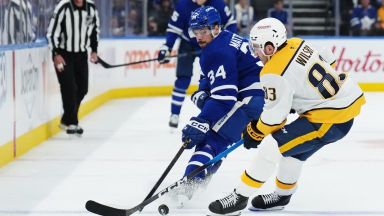 Toronto Maple Leafs' Auston Matthews (34) and Nashville Predators' Adam Wilsby (83) battle for the puck during second period NHL hockey action in Toronto on Tuesday, October 14, 2025. (Nathan Denette/CP)