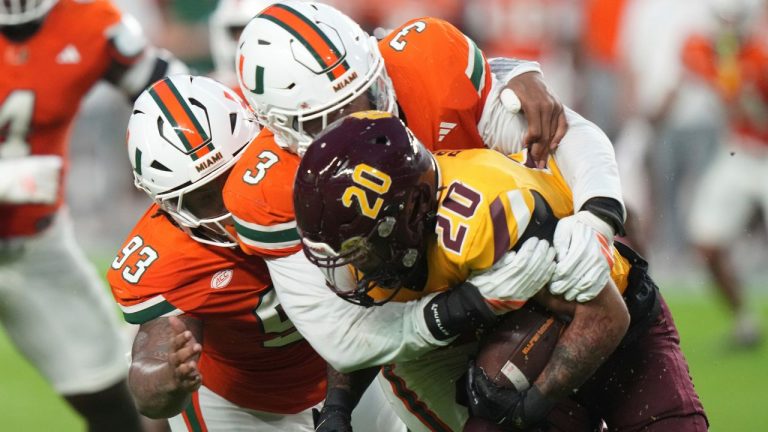 Bethune-Cookman running back Juan Rodriguez (20) runs as he is tackled by Miami Hurricanes defensive lineman Donta Simpson (93) and defensive lineman Akheem Mesidor (3) during the first half of an NCAA college football game, Saturday, Sept. 6, 2025, in Miami Gardens, Fla. (Lynne Sladky/AP Photo)