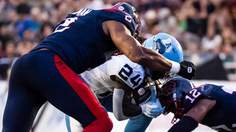 Toronto Argonauts' Deonta McMahon (24) scores while Montreal Alouettes' Shawn Oakman (2) and Najee Murray (12) tackle during first half CFL action in Montreal on Thursday, July 17, 2025. (Christopher Katsarov/THE CANADIAN PRESS)