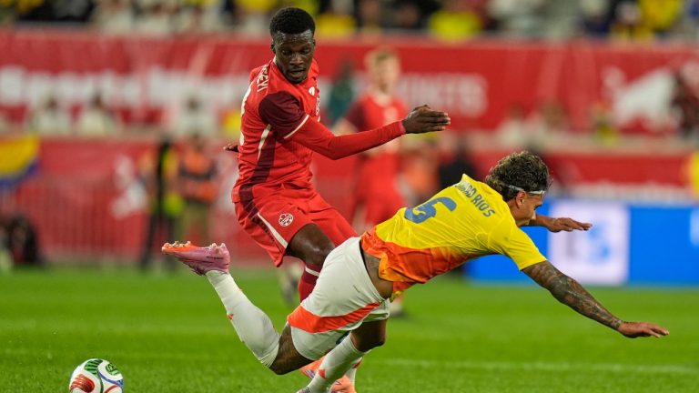 Colombia's Richard Ríos, right, falls while competing for the ball with Canada's Tani Oluwaseyi during the first half of a friendly soccer match in Harrison, N.J., Tuesday, Oct. 14, 2025. (Seth Wenig/AP)