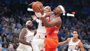 Oklahoma City Thunder guard Shai Gilgeous-Alexander, center right, shoots around Phoenix Suns guard Jordan Goodwin, center left, during the second half of an NBA Cup basketball game, Friday, Nov. 28, 2025, in Oklahoma City. (Kyle Phillips/AP)