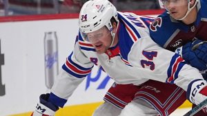 New York Rangers right wing Arthur Kaliyev, left, pursues the puck with Colorado Avalanche defenseman Sam Malinski in the second period of an NHL hockey game, Tuesday, Jan. 14, 2025, in Denver. (AP Photo/David Zalubowski)