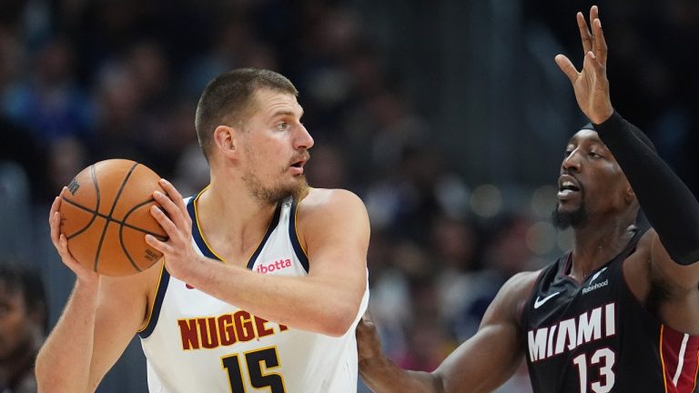 Denver Nuggets centre Nikola Jokic, left, looks to pass the ball as Miami Heat center Bam Adebayo defends in the first half of an NBA basketball game Wednesday, Nov. 5, 2025, in Denver. (David Zalubowski/AP)