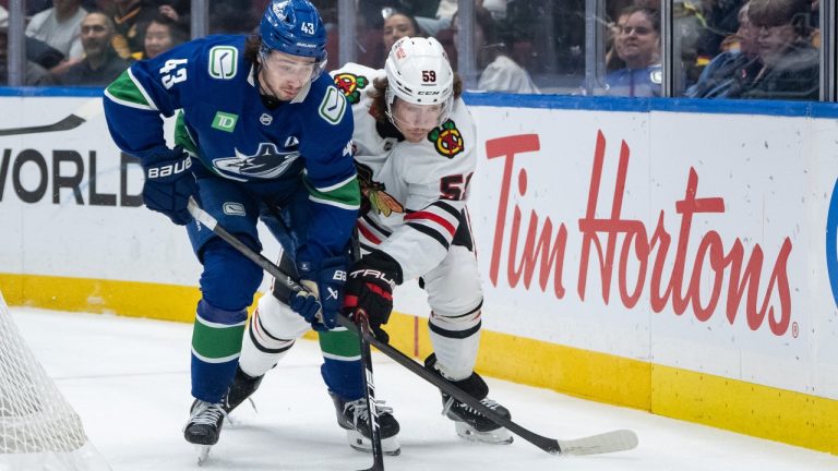 Vancouver Canucks' Quinn Hughes (43) and Chicago Blackhawks' Tyler Bertuzzi (59) vie for the puck during the first period of an NHL hockey game in Vancouver, on Wednesday, November 5, 2025. (Ethan Cairns/CP)