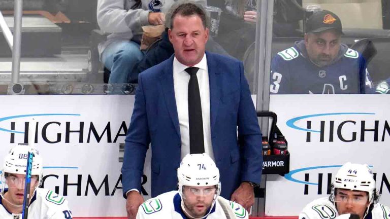 Vancouver Canucks head coach Adam Foote stands behind his bench during the first period of an NHL hockey game against the Pittsburgh Penguins in Pittsburgh, Tuesday, Oct. 21, 2025. (Gene J. Puskar/AP)