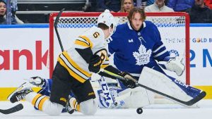 Toronto Maple Leafs goaltender Dennis Hildeby (35) loses his helmet as Boston Bruins' Mason Lohrei (6) searches for the puck during second period NHL hockey action in Toronto, on Saturday, Nov. 8, 2025. (Sammy Kogan/CP)