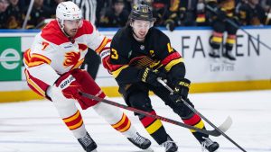 Calgary Flames' Kevin Bahl and Vancouver Canucks' Quinn Hughes vie for the puck during first period NHL action in Vancouver, on Sunday, November 23, 2025. (Ethan Cairns/CP)