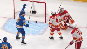 St. Louis Blues' Dylan Holloway (81) celebrates after scoring past Calgary Flames goaltender Dustin Wolf (32) as Flames' Rasmus Andersson (4) and Kevin Bahl (7) watch during the first period of an NHL hockey game Tuesday, Nov. 11, 2025, in St. Louis. (Jeff Roberson/AP)