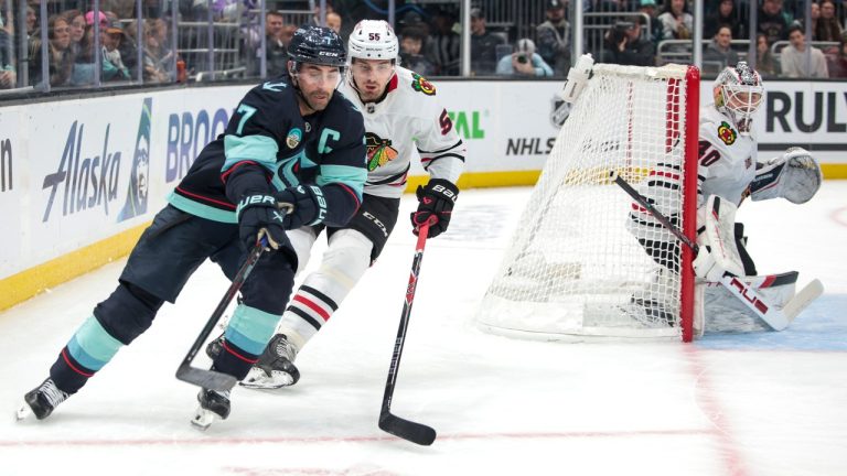 Seattle Kraken right wing Jordan Eberle (7) and Chicago Blackhawks defenseman Artyom Levshunov (55) compete for the puck as goalie Arvid Soderblom (40) looks on during the first period of an NHL hockey game Monday, Nov. 3, 2025, in Seattle. (Jason Redmond/AP)