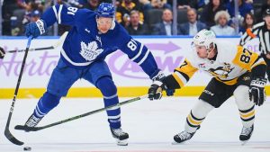 Toronto Maple Leafs' Dakota Joshua (81) and Pittsburgh Penguins' Sidney Crosby (87) battle for the puck during second period NHL hockey action in Toronto, on Monday, Nov. 3, 2025. (Sammy Kogan/CP)