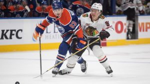 Chicago Blackhawks' Connor Bedard (right) and Edmonton Oilers' Ryan Nugent-Hopkins (93) battle for the puck during first period NHL action, in Edmonton on Saturday, November 1, 2025. THE CANADIAN PRESS/Jason Franson
