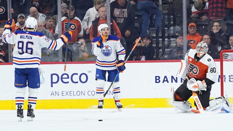 Edmonton Oilers' Jack Roslovic, centre, accompanied by Jake Walman, celebrates after scoring on Philadelphia Flyers goaltender Dan Vladar in overtime of an NHL hockey game, Wednesday, Nov. 12, 2025, in Philadelphia. (Matt Rourke/AP)