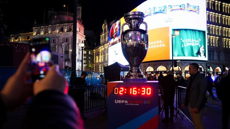 Fans take photos of a replica European Championships soccer trophy and countdown clock at Piccadilly Circus in London, Wednesday, Nov. 12, 2025. (James Manning/PA via AP)