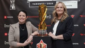 Diana Matheson, left, co-founder and chief growth officer of the Northern Super League, and NSL president Christina Litz pose in Toronto, on Thursday, Nov. 13, 2025, next to the Diana B. Matheson Cup, which will be awarded after Saturday's championship game between AFC Toronto and Vancouver Rise FC. (CP/Neil Davidson)