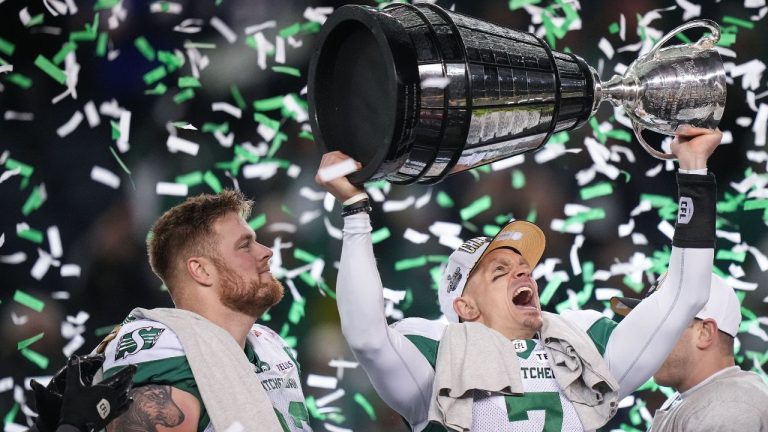 Saskatchewan Roughriders quarterback Trevor Harris hoists the Grey Cup as Logan Ferland, left, watches after Saskatchewan defeated the Montreal Alouettes during the 112th CFL Grey Cup, in Winnipeg, Sunday, Nov. 16, 2025. (THE CANADIAN PRESS/Darryl Dyck)