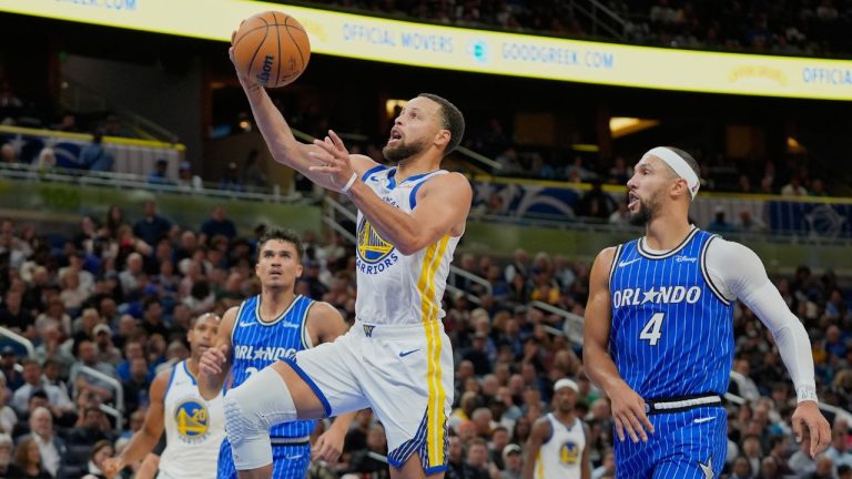 Golden State Warriors guard Stephen Curry, center, gets past Orlando Magic guard Jalen Suggs (4) and forward Tristan da Silva, left, during the second half of an NBA game, Tuesday, Nov. 18, 2025, in Orlando, Fla. (AP Photo/John Raoux)