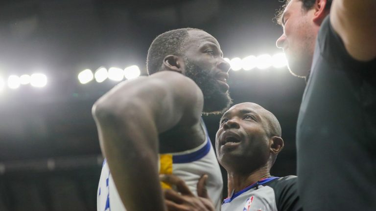 Golden State Warriors forward Draymond Green is held back by referee Courtney Kirkland while talking to New Orleans Pelicans fan Sam Green during the first half of an NBA basketball game against the New Orleans Pelicans in New Orleans, Sunday, Nov. 16, 2025. (David Grunfeld/The Times-Picayune via AP)