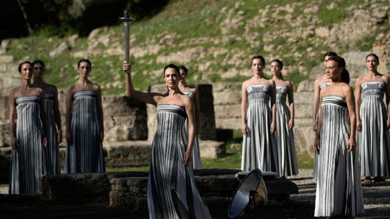 Actor Mary Mina playing the role of high priestess, center, performs during a rehearsal ahead of the flame lighting for the Milan Cortina 2026 Winter Olympics, at the Ancient Olympia site, Greece, Monday, Nov. 24, 2025. (Petros Giannakouris/AP)