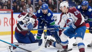 Colorado Avalanche goalie MacKenzie Blackwood (39) makes the save after losing his stick as Vancouver Canucks' Elias Pettersson (40) and Evander Kane (91) and Colorado's Nathan MacKinnon (29) watch during the third period of an NHL hockey game in Vancouver, B.C., Sunday, Nov. 9, 2025. (Darryl Dyck/CP)
