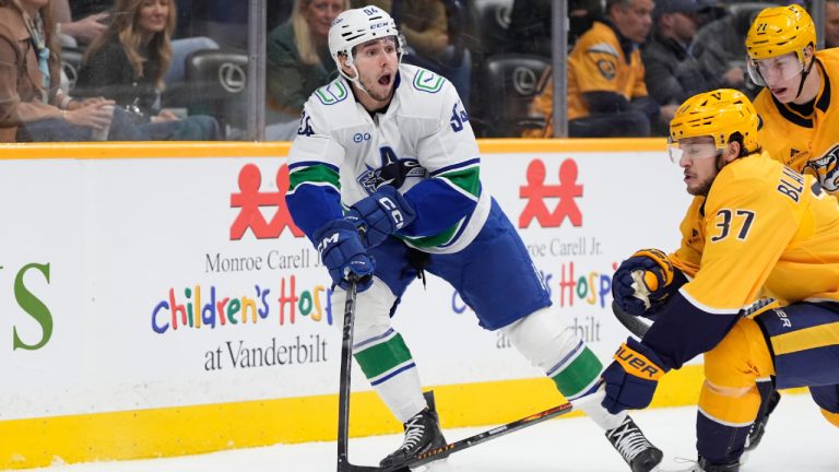Vancouver Canucks centre Linus Karlsson (94) passes the puck around Nashville Predators defenseman Nick Blankenburg (37) during the first period of an NHL hockey game Monday, Nov. 3, 2025, in Nashville, Tenn. (George Walker IV/AP)