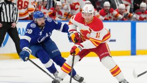 Calgary Flames centre Mikael Backlund (11) gets by Tampa Bay Lightning left wing Nick Paul (20) during the first period of an NHL hockey game Thursday, Feb. 27, 2025, in Tampa, Fla. (Chris O'Meara/AP)