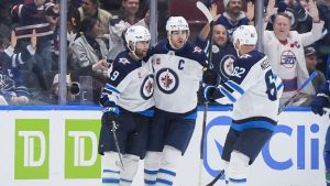 Winnipeg Jets' Alex Iafallo (9), Adam Lowry (17) and Nino Niederreiter (62) celebrate Iafallo's empty net goal as Vancouver Canucks' Jake DeBrusk (74) and Filip Hronek (17) look on during the third period of an NHL hockey game in Vancouver, on Tuesday, November 11, 2025. (Darryl Dyck/CP)