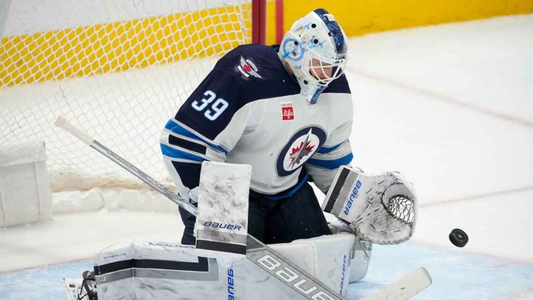 Former Winnipeg Jets goaltender Laurent Brossoit reaches out to glove a shot from the Dallas Stars during the first period of an NHL game. (Tony Gutierrez/AP)