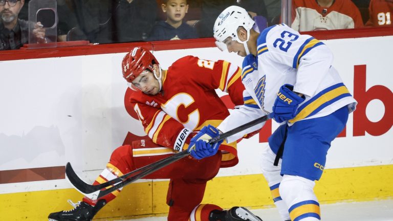 St. Louis Blues' Logan Mailloux, right, battles for the puck with Calgary Flames' Matt Coronato during second period NHL hockey action in Calgary, Saturday, Oct. 11, 2025. (Jeff McIntosh/CP)