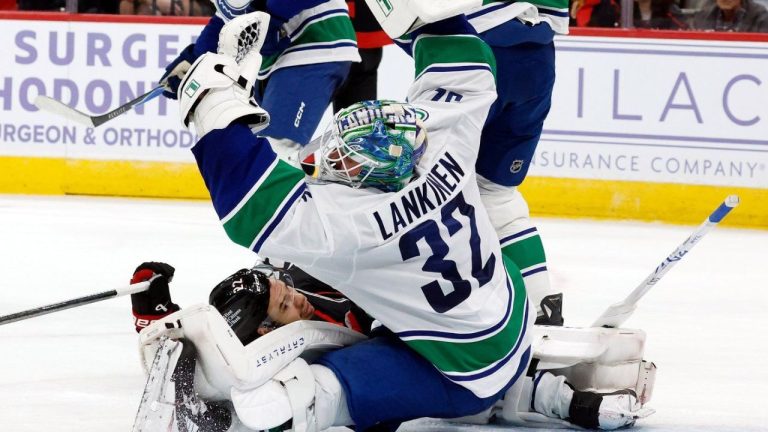 Vancouver Canucks' Kevin Lankinen (32) snares the puck in front of a crashing Carolina Hurricanes' Logan Stankoven (22) during the second period of an NHL hockey game in Raleigh, N.C., Friday, Nov. 14, 2025. (Karl DeBlaker/AP)