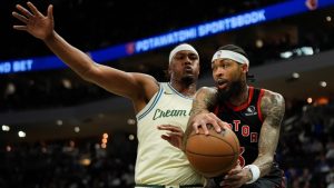 Toronto Raptors' Brandon Ingram, right, looks to pass the ball around Milwaukee Bucks' Myles Turner, left, during the first half of an NBA basketball game Thursday, Dec. 18, 2025, in Milwaukee. (AP Photo/Aaron Gash)