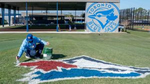 A painter touches up the Toronto Blue Jays logo on the training hill at the Spring Training facility in Dunedin, Fla. on Wednesday, February 21, 2024. (Frank Gunn/CP)