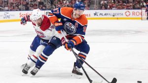 Montreal Canadiens' Nick Suzuki (14) and Edmonton Oilers' Connor McDavid (97) battle for the puck during overtime NHL action in Edmonton on Thursday, March 6, 2025. (Jason Franson/CP)