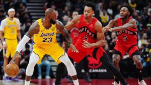 Los Angeles Lakers' LeBron James (23) protects the ball from Toronto Raptors' Scottie Barnes (4) and Immanuel Quickley (5) during first half NBA basketball action in Toronto on Thursday, Dec. 4, 2025. THE CANADIAN PRESS/Frank Gunn