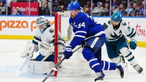 Toronto Maple Leafs' Auston Matthews moves the puck past San Jose Sharks' Mario Ferraro as Sharks goaltender Alex Nedeljkovic looks on during second period NHL action in Toronto on Thursday, Dec. 11, 2025. (Frank Gunn/CP)