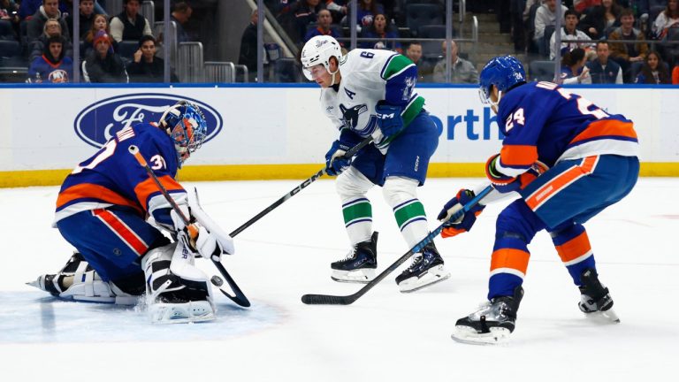 New York Islanders goaltender Ilya Sorokin, left, makes a save against Vancouver Canucks right wing Brock Boeser (6) during the first period of an NHL hockey game, Friday, Dec. 19, 2025, in Elmont, N.Y. (AP Photo/Noah K. Murray)
