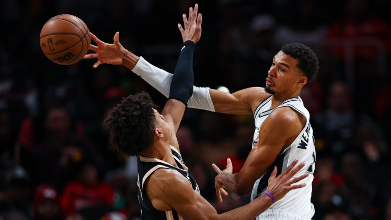 Atlanta Hawks forward Jalen Johnson, left, defends against San Antonio Spurs forward Victor Wembanyama, during the first half of an NBA basketball game, Friday, Dec. 19, 2025, in Atlanta. (AP Photo/Colin Hubbard)