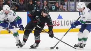 Seattle Kraken centre Chandler Stephenson (9) tries to regain control of the puck against Vancouver Canucks defenceman Marcus Pettersson (29) and centre Max Sasson (63) during the first period of an NHL hockey game Monday, Dec. 29, 2025, in Seattle. (Lindsey Wasson/AP)
