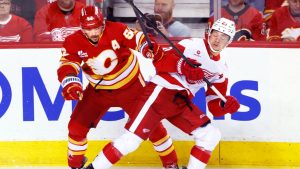 Detroit Red Wings' Lucas Raymond, right, battles against Calgary Flames' MacKenzie Weegar during second period NHL hockey action in Calgary, on Wednesday, Dec. 10, 2025. (Larry MacDougal/CP)