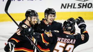 Calgary Flames' Yegor Sharangovich, centre, celebrates his goal with teammates Joel Farabee, left, and MacKenzie Weegar during first period NHL hockey action against the Buffalo Sabres in Calgary, Alta., Monday, Dec. 8, 2025. (Jeff McIntosh/CP)