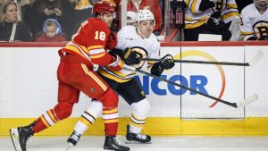 Boston Bruins' Michael Eyssimont, right, is checked by Calgary Flames' John Beecher during first period NHL hockey action in Calgary on Monday, Dec. 29, 2025. (Jeff McIntosh/CP)