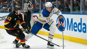 Buffalo Sabres' Tage Thompson (right) tries to fight off the check of Vancouver Canucks' Quinn Hughes during first period NHL hockey action in Vancouver on Thursday, Dec. 11, 2025. (Rich Lam/CP)