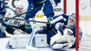 Vancouver Canucks goaltender Kevin Lankinen (32) stops the puck as Utah Mammoth's Daniil But (19) watches during the first period of an NHL hockey game in Vancouver, on Friday, December 5, 2025. (Ethan Cairns/CP)