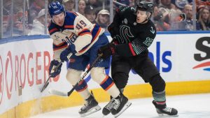 Seattle Kraken's Tye Kartye (12) checks Edmonton Oilers' Ty Emberson (49) during first period NHL action, in Edmonton on Thursday, December 4, 2025. (Jason Franson/CP)